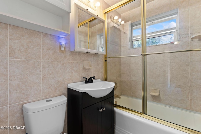 full bathroom featuring tile walls, vanity, bath / shower combo with glass door, and toilet