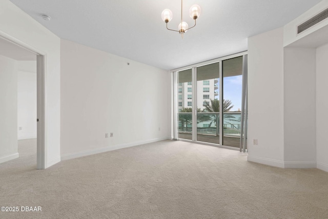 carpeted empty room featuring baseboards, a wall of windows, visible vents, and a notable chandelier