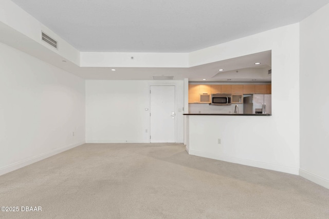 unfurnished living room with light carpet, baseboards, visible vents, a raised ceiling, and recessed lighting