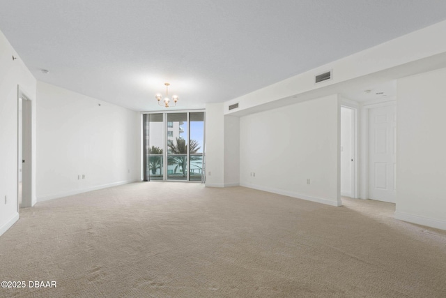 unfurnished room with an inviting chandelier, floor to ceiling windows, visible vents, and light colored carpet