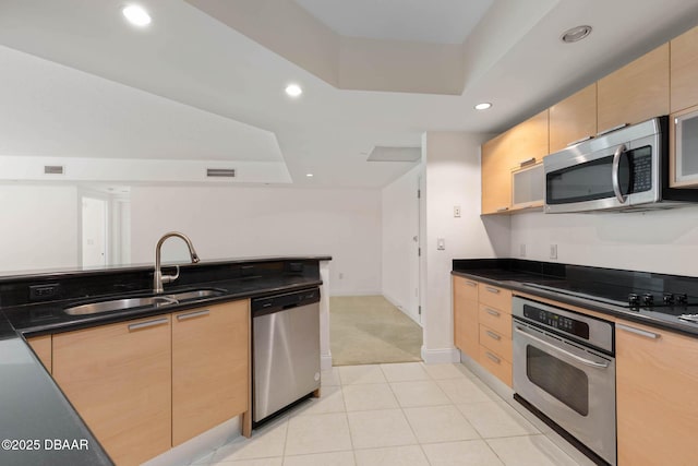 kitchen featuring a sink, stainless steel appliances, light brown cabinetry, and a raised ceiling