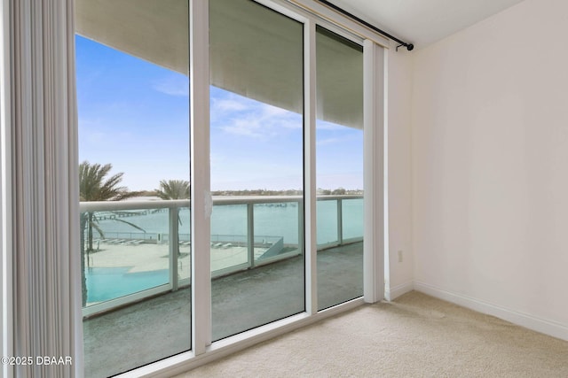 unfurnished room featuring carpet, a water view, and baseboards