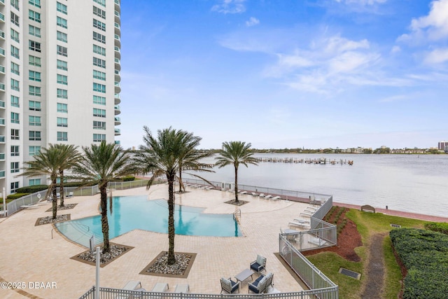 pool featuring a water view, fence, and a patio