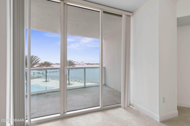 doorway to outside with carpet floors, a wall of windows, and baseboards