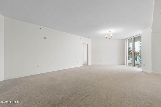 unfurnished room with light carpet, expansive windows, baseboards, and a notable chandelier