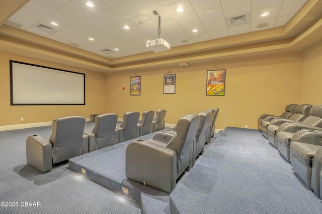 carpeted home theater with a tray ceiling, visible vents, and baseboards