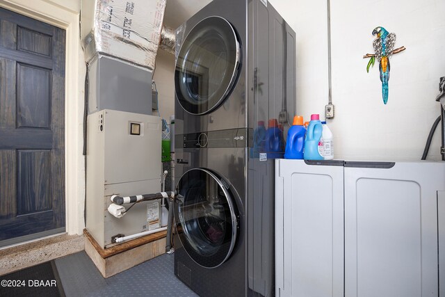 clothes washing area with stacked washing maching and dryer