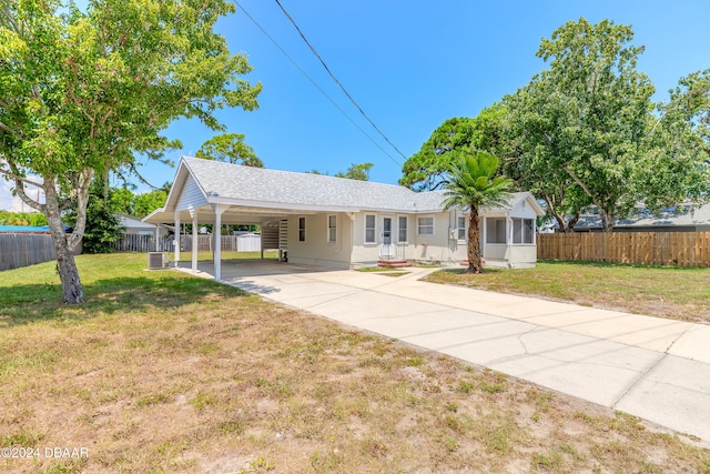 ranch-style home with a front yard, central air condition unit, and a carport