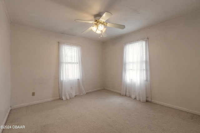 carpeted spare room with ceiling fan and plenty of natural light