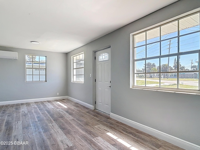 foyer entrance featuring an AC wall unit, wood finished floors, and baseboards