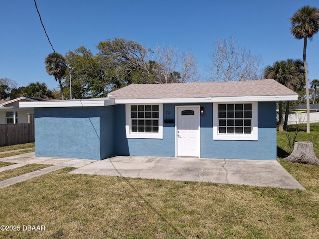 view of front facade with stucco siding, a front yard, and fence