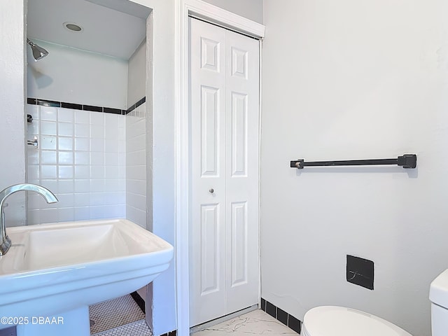 bathroom featuring baseboards, walk in shower, toilet, a closet, and a sink