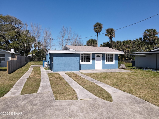 view of front facade with stucco siding, driveway, a front yard, and fence