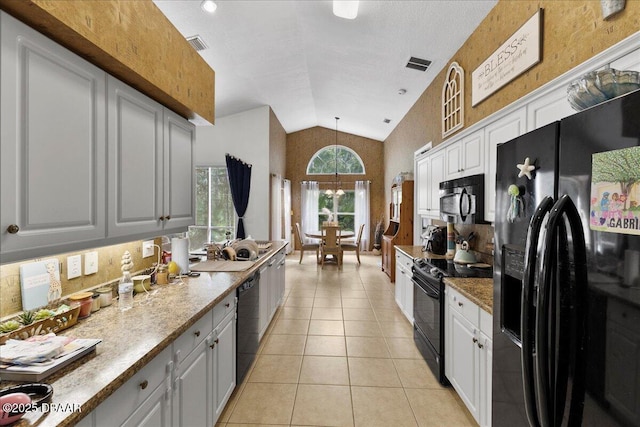 684 Aldenham Ln, Ormond Beach, FL 32174 - kitchen with black appliances, vaulted ceiling, light tile patterned floors, decorative light fixtures, and white cabinetry