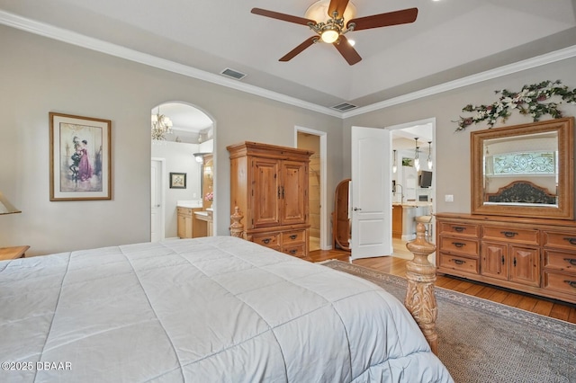 109 Edward Dr, Palm Coast, FL 32164 - bedroom with connected bathroom, hardwood / wood-style floors, arched walkways, crown molding, and a tray ceiling
