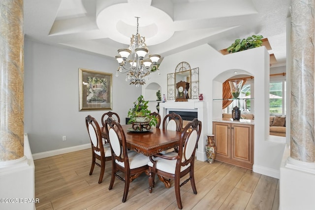 109 Edward Dr, Palm Coast, FL 32164 - dining space with light wood-style flooring, a fireplace, a chandelier, coffered ceiling, and arched walkways