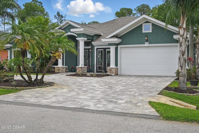 109 Edward Dr, Palm Coast, FL 32164 - view of front of house featuring decorative driveway, stucco siding, an attached garage, a shingled roof, and stone siding