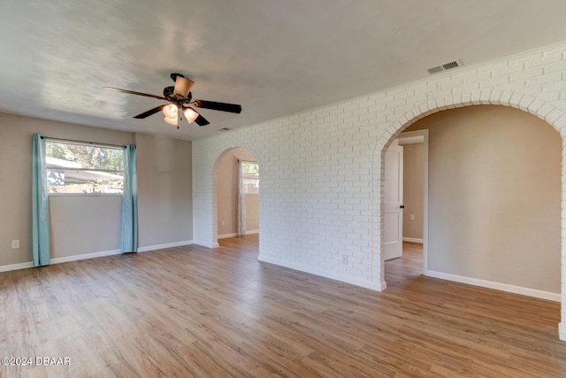 13 Highridge Rd, Daytona Beach, FL 32117 - spare room featuring arched walkways, brick wall, a ceiling fan, and wood finished floors