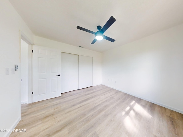 unfurnished bedroom featuring light hardwood / wood-style floors, ceiling fan, and a closet