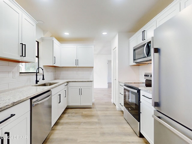 kitchen featuring light stone counters, appliances with stainless steel finishes, sink, light hardwood / wood-style floors, and white cabinets