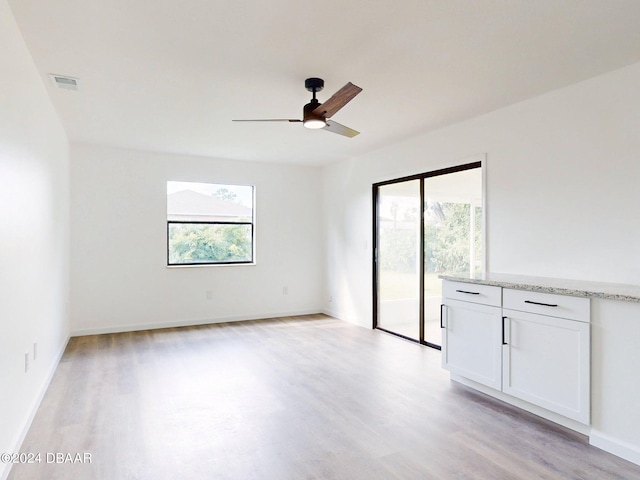 unfurnished room featuring light hardwood / wood-style floors, ceiling fan, and a healthy amount of sunlight