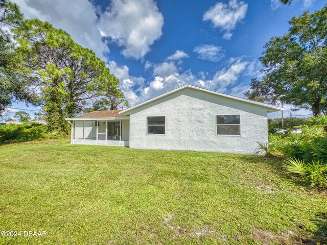 rear view of property featuring a sunroom and a yard