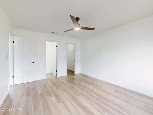 unfurnished bedroom with light hardwood / wood-style flooring, ceiling fan, a spacious closet, and a closet