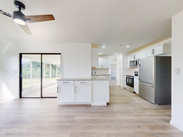 kitchen featuring white cabinets, stainless steel appliances, light stone counters, and light hardwood / wood-style flooring