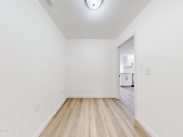 spare room with a textured ceiling and light hardwood / wood-style flooring