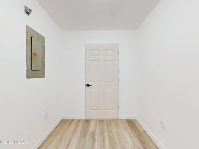 unfurnished room featuring electric panel and light hardwood / wood-style floors