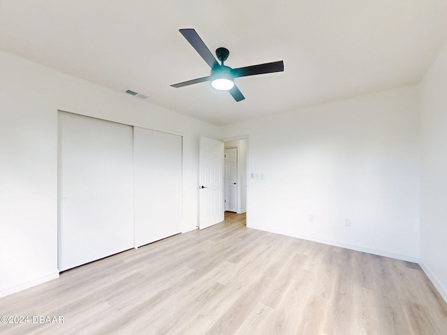 unfurnished bedroom featuring light hardwood / wood-style floors, ceiling fan, and a closet