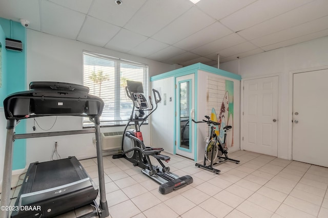 exercise room with a drop ceiling and light tile patterned floors