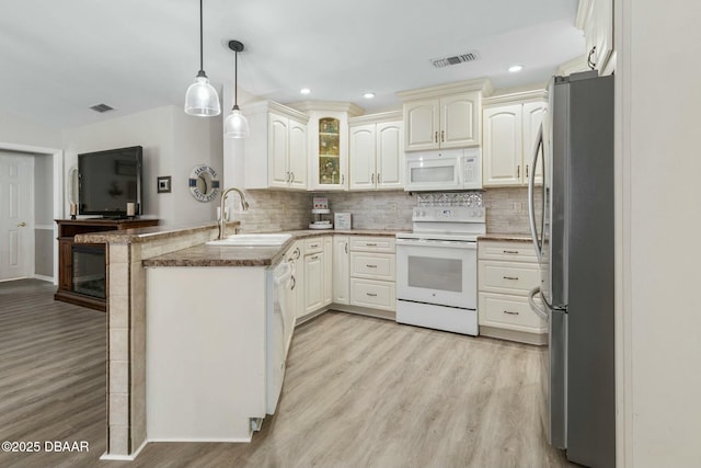 kitchen featuring white appliances, light wood-type flooring, kitchen peninsula, pendant lighting, and sink