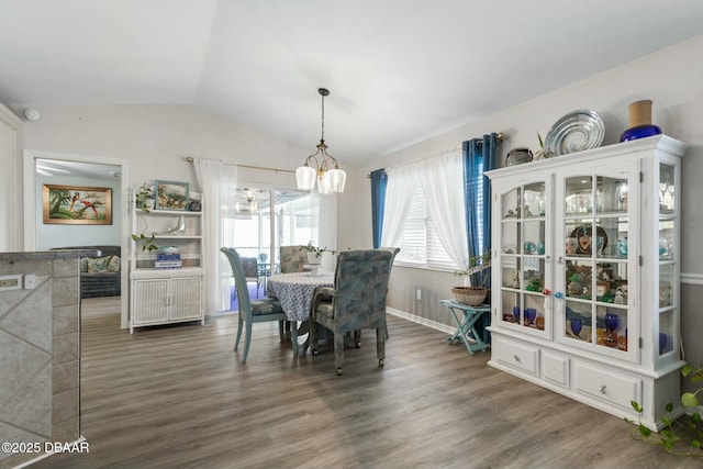 dining area with a notable chandelier, vaulted ceiling, and dark hardwood / wood-style flooring