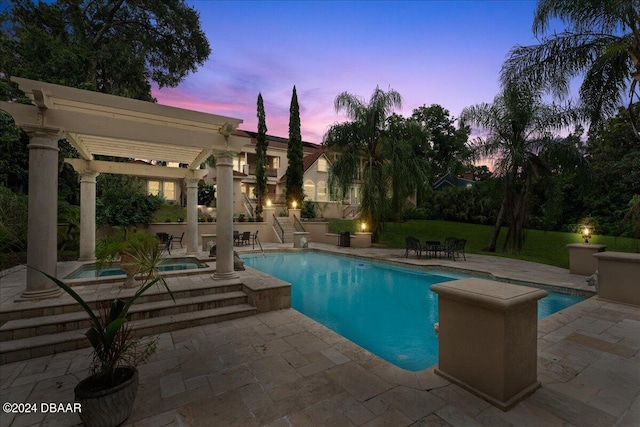 pool at dusk featuring a patio area and an in ground hot tub