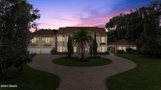 mediterranean / spanish-style house featuring a garage and a lawn