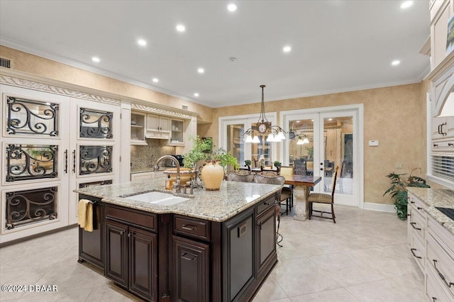 kitchen with sink, an inviting chandelier, dark brown cabinets, crown molding, and pendant lighting