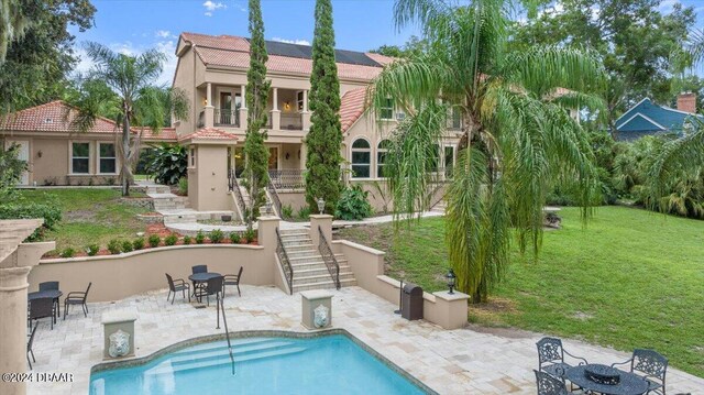 rear view of property with a patio, a lawn, and a balcony