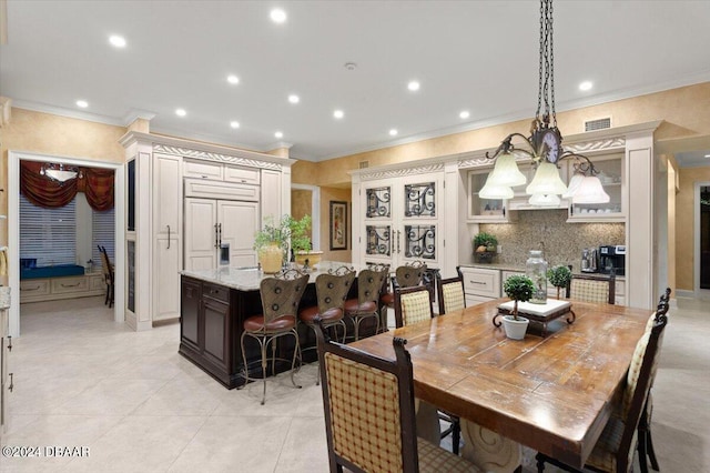 tiled dining area with crown molding and an inviting chandelier