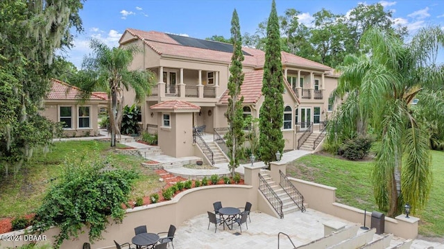 back of property featuring a patio area, a lawn, and a balcony