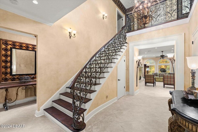 stairway with a towering ceiling, ceiling fan, and crown molding