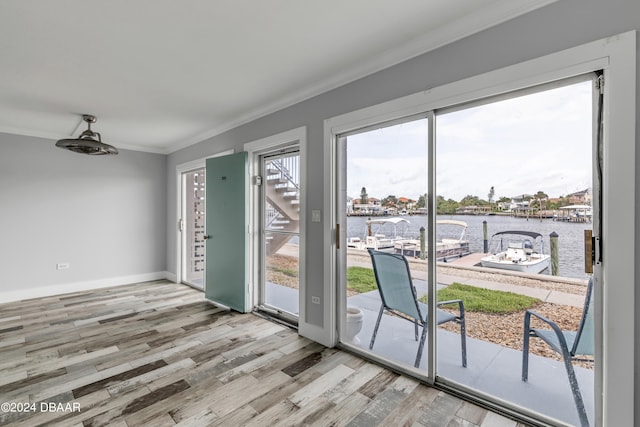 doorway to outside featuring light wood-type flooring, a healthy amount of sunlight, a water view, and ornamental molding