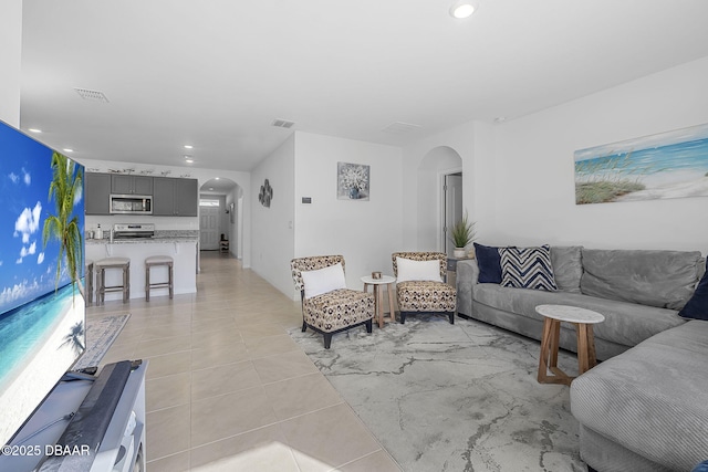 living area with arched walkways, visible vents, and recessed lighting