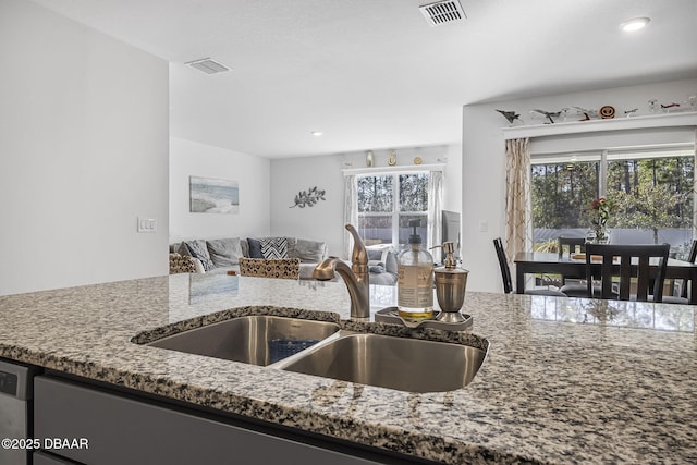 kitchen with stone counters, visible vents, and a sink