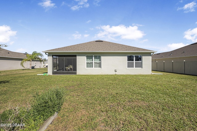 rear view of house with a sunroom, a lawn, fence, and stucco siding