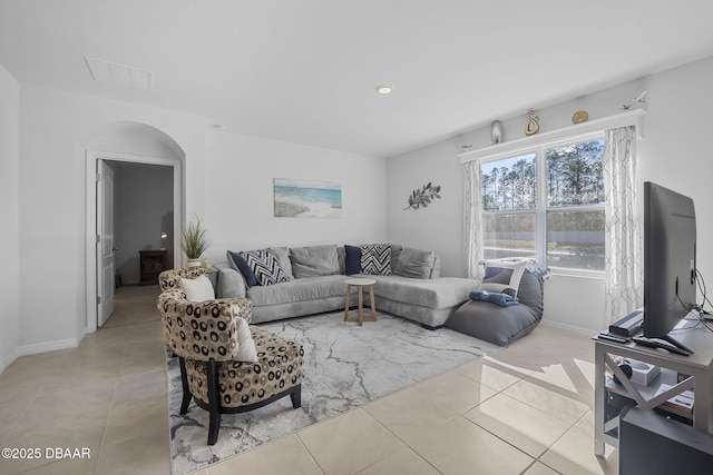 tiled living area with arched walkways, visible vents, and baseboards