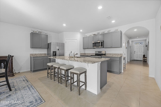 kitchen with stainless steel appliances, arched walkways, gray cabinets, and a sink