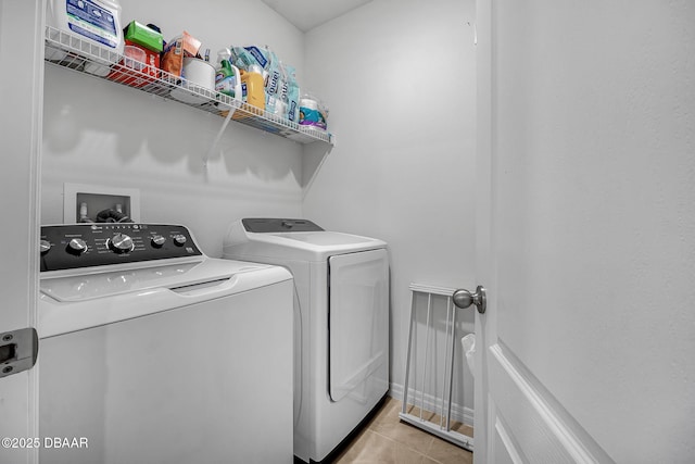 washroom with light tile patterned floors, laundry area, washing machine and clothes dryer, and baseboards