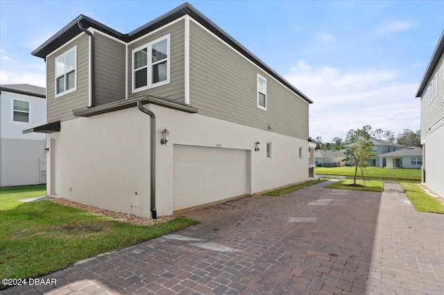 view of side of property featuring a garage and a lawn