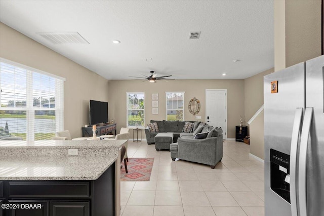 living room featuring a wealth of natural light, ceiling fan, a textured ceiling, and light tile patterned flooring